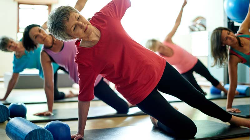 Aula de ginástica com mulheres de várias idades - alusão ao exercício físico que previne as quedas